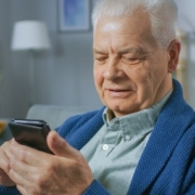 Senior man on couch checking his phone for email