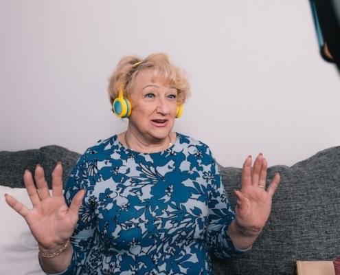 Senior woman on couch with headphones creating a TikTok