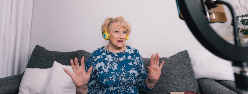 Senior woman on couch with headphones creating a TikTok