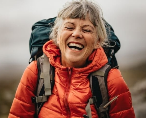 Senior woman outdoors hiking with backpack.