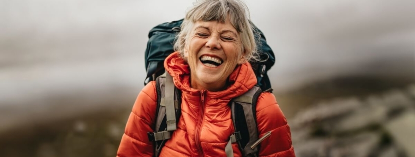 Senior woman outdoors hiking with backpack.
