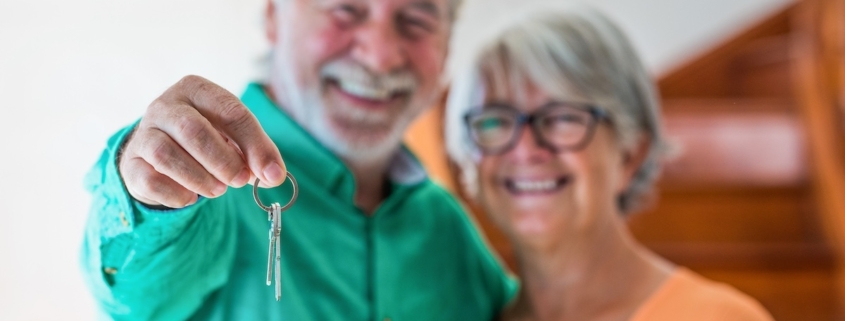 portrait and close up of Two happy seniors buying a new house holding the key with his hand.