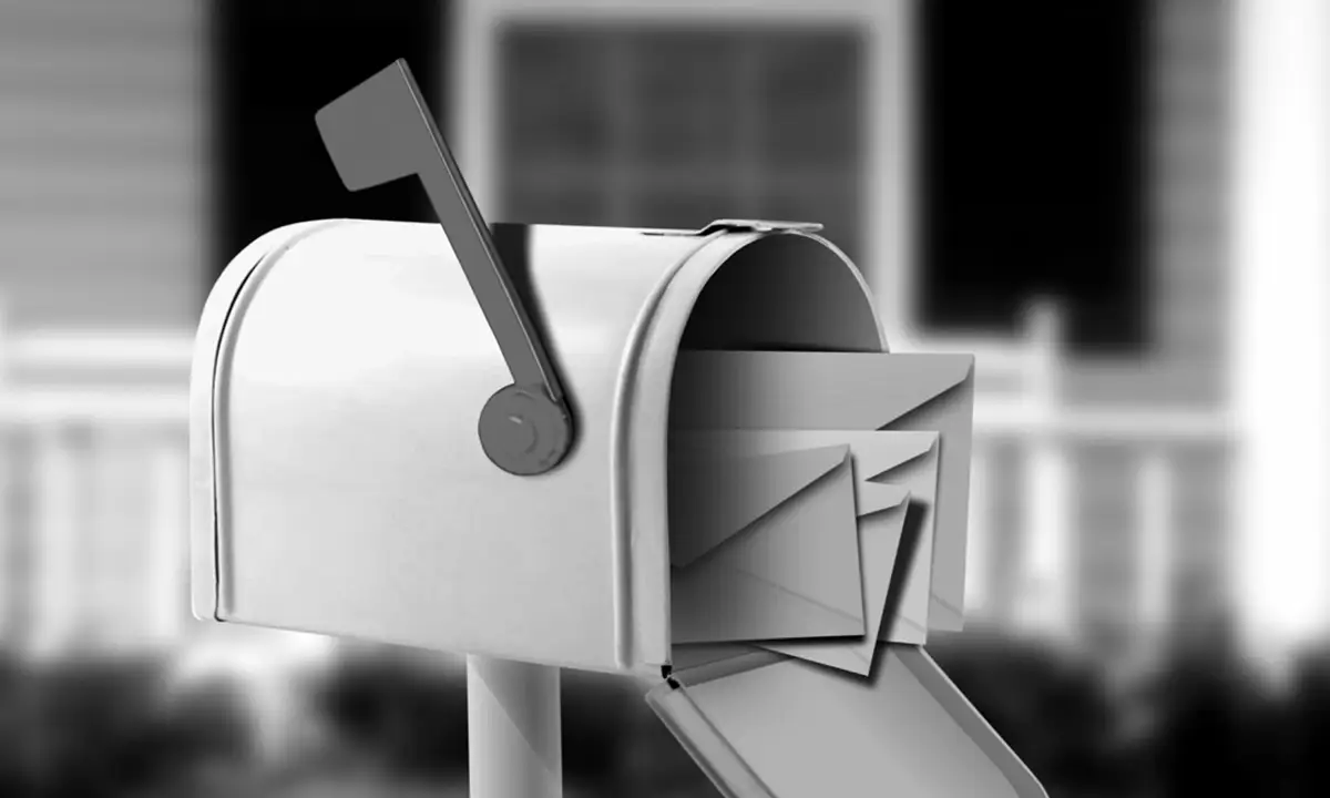 A mailbox with its door open and several envelopes inside and spilling out, positioned in front of a house.