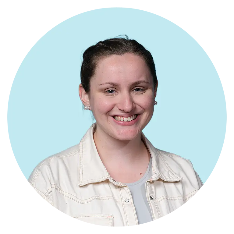 A woman with brown hair tied back, wearing a light-colored jacket over a top, smiles at the camera against a light blue background with a digital distortion effect on the right side.