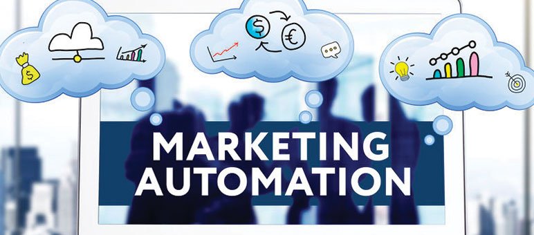 A digital screen displays "MARKETING AUTOMATION" with cloud-shaped icons overhead—featuring money, charts, and ideas—capturing the essence of marketing automation. Silhouetted people stand in the background.