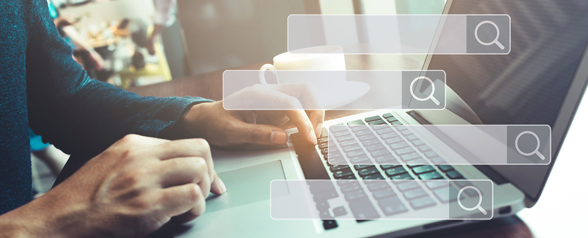 Person typing on a laptop with three digital search bar graphics overlayed in the foreground, illustrating the importance of a strong senior living marketing strategy; a coffee cup is visible in the background.