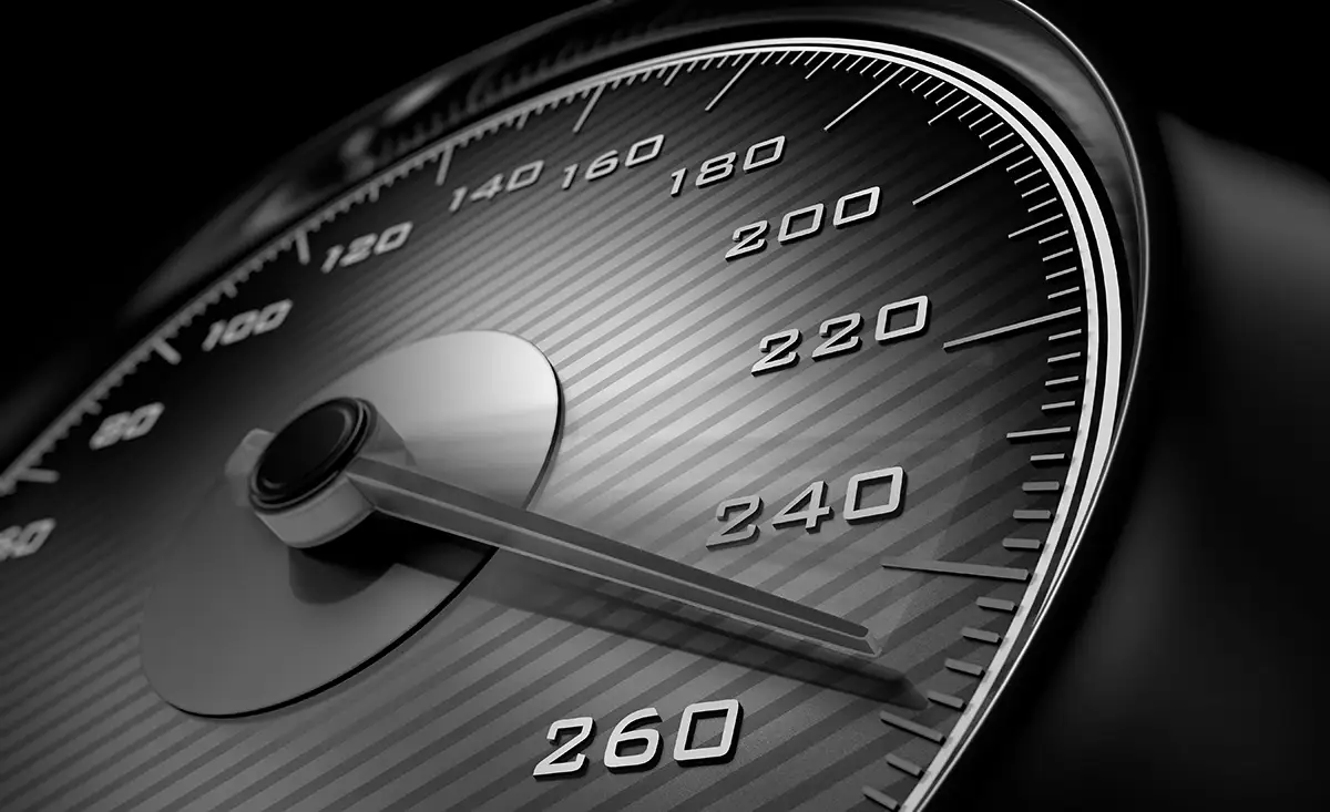 Close-up of a car speedometer with the needle pointing at approximately 240, featuring a black and metallic design with clear numerical markings up to 260.