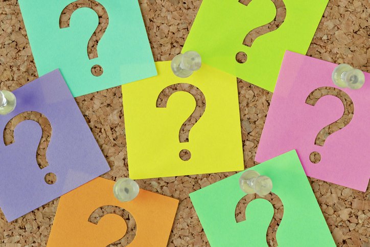Colorful sticky notes with cut-out question marks are pinned to a corkboard, sparking creative ideas for senior living sales strategies.